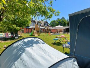 Caravan met voortent en losse tent naast de speelpek en met zicht op zwembad